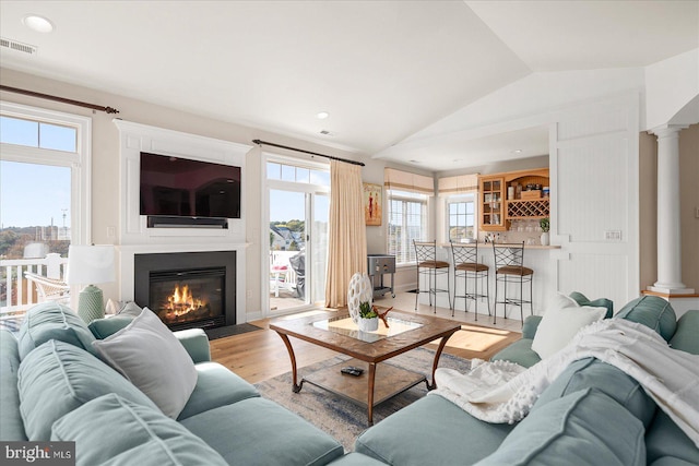 living room featuring lofted ceiling, light hardwood / wood-style flooring, a fireplace, and plenty of natural light