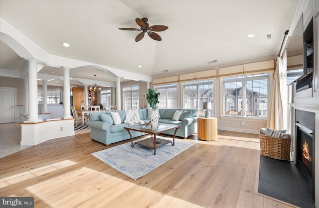 living room featuring light wood-type flooring, plenty of natural light, and ceiling fan with notable chandelier