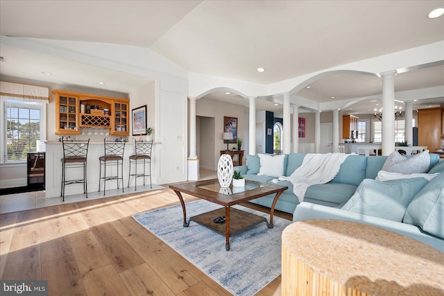 living room featuring a chandelier, vaulted ceiling, and light wood-type flooring