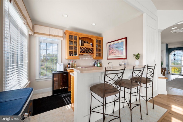 bar featuring wine cooler, decorative backsplash, and light hardwood / wood-style flooring