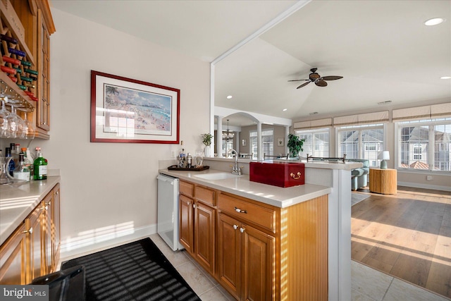 kitchen with white dishwasher, sink, light hardwood / wood-style flooring, and kitchen peninsula