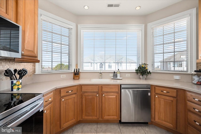 kitchen with a healthy amount of sunlight, stainless steel appliances, light tile patterned floors, and sink