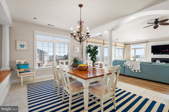 dining room with ornate columns, light tile patterned flooring, and ceiling fan with notable chandelier