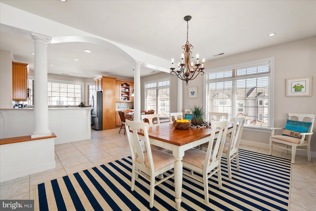 tiled dining area featuring ornate columns and a notable chandelier