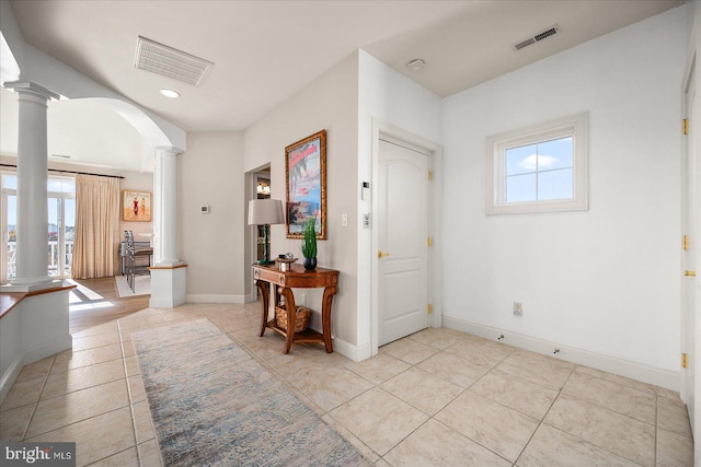 entryway with light tile patterned flooring, ornate columns, and plenty of natural light