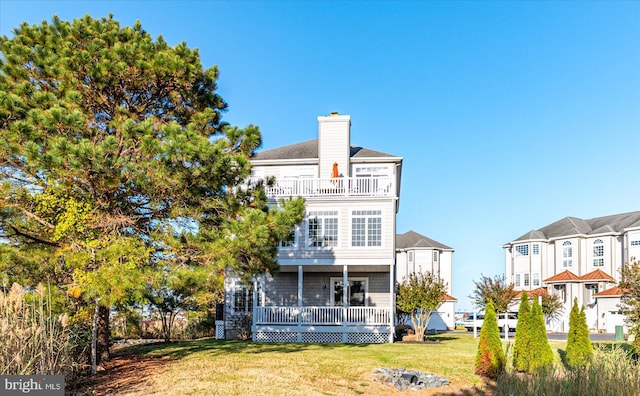 rear view of house with a wooden deck, a lawn, and a balcony