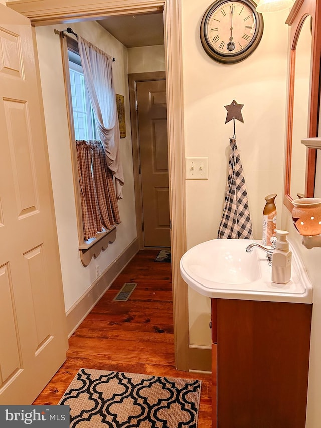 bathroom with baseboards, visible vents, wood finished floors, and vanity