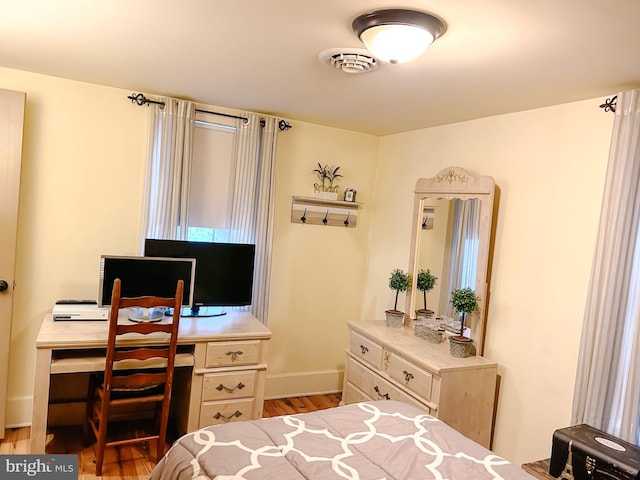 bedroom with light wood-style floors, visible vents, and baseboards