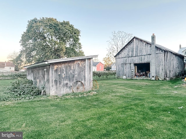 view of barn featuring fence and a yard