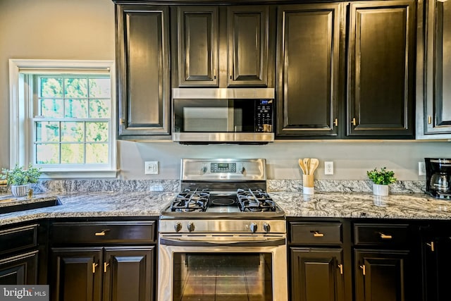 kitchen featuring dark brown cabinets, light stone counters, and stainless steel appliances