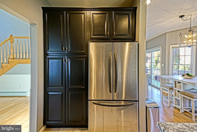 kitchen featuring an inviting chandelier, stainless steel fridge, light hardwood / wood-style flooring, vaulted ceiling, and hanging light fixtures