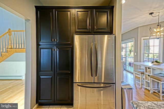 kitchen with light wood-type flooring, freestanding refrigerator, a baseboard radiator, and a chandelier