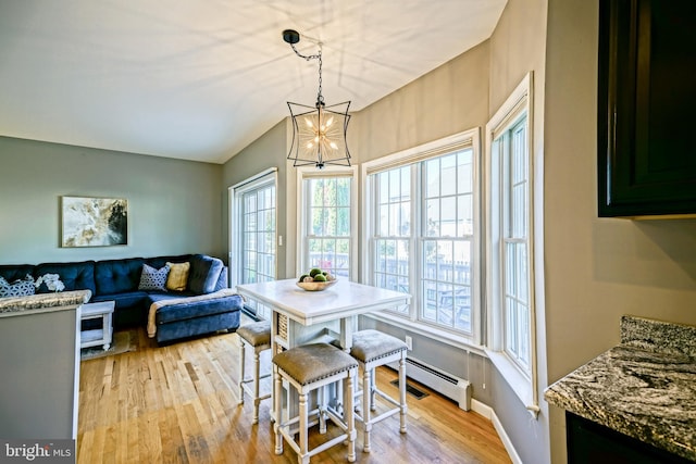 dining room featuring a notable chandelier, a baseboard heating unit, baseboards, light wood-style floors, and lofted ceiling