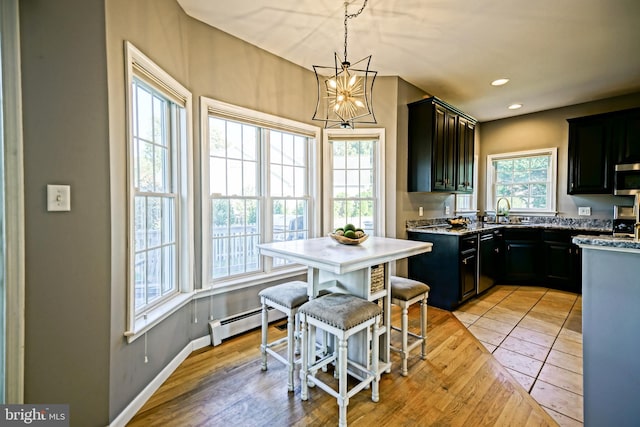 kitchen featuring sink, a baseboard heating unit, light hardwood / wood-style floors, a notable chandelier, and decorative light fixtures