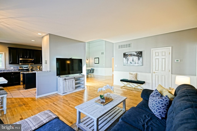 living room featuring light wood-type flooring, wainscoting, visible vents, and recessed lighting