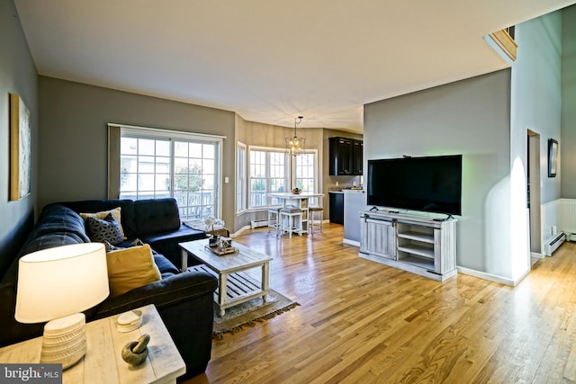 living room with an inviting chandelier, a baseboard heating unit, and light hardwood / wood-style floors