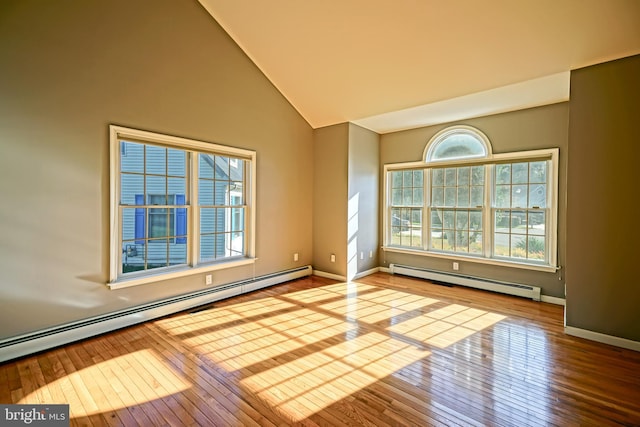 unfurnished room with vaulted ceiling, a baseboard heating unit, and hardwood / wood-style floors