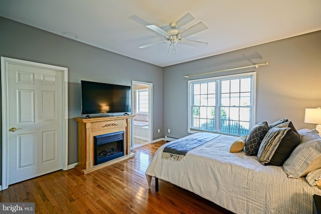 bedroom with a baseboard radiator, wood finished floors, a fireplace, and baseboards