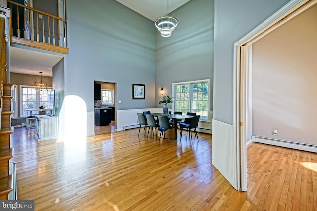 dining room featuring a wealth of natural light, a notable chandelier, a towering ceiling, and a baseboard heating unit