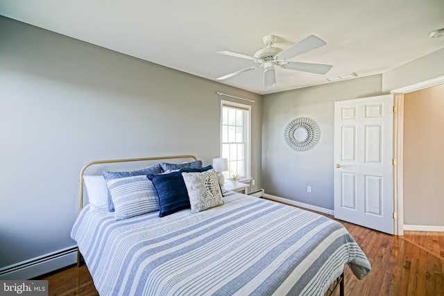 bedroom with ceiling fan, hardwood / wood-style floors, and a baseboard heating unit