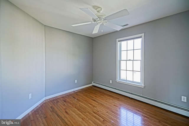 unfurnished room with visible vents, ceiling fan, a baseboard heating unit, and wood finished floors