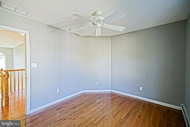 unfurnished room with visible vents, baseboards, a ceiling fan, wood finished floors, and a baseboard heating unit