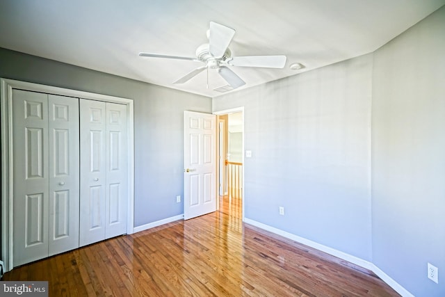 unfurnished bedroom featuring a closet, baseboards, ceiling fan, and wood finished floors