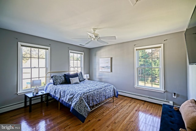 bedroom with a ceiling fan, hardwood / wood-style floors, and baseboard heating