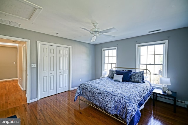 bedroom with ceiling fan, a closet, baseboard heating, and dark hardwood / wood-style flooring