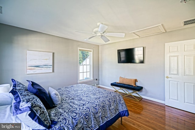bedroom featuring a ceiling fan, visible vents, wood finished floors, attic access, and baseboards