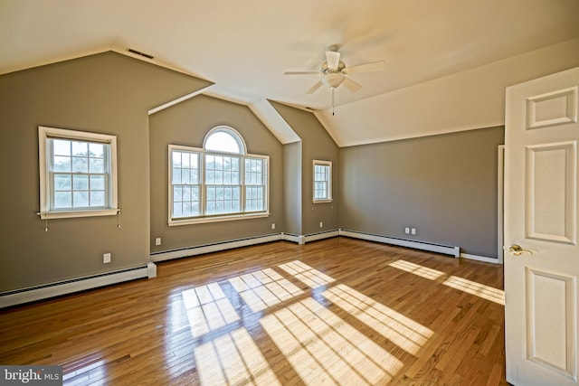 spare room featuring ceiling fan, baseboard heating, lofted ceiling, and light hardwood / wood-style flooring