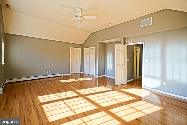 unfurnished bedroom featuring lofted ceiling, ceiling fan, wood-type flooring, two closets, and a baseboard heating unit