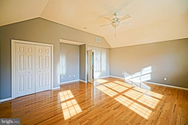 unfurnished bedroom featuring a closet, wood finished floors, baseboards, and lofted ceiling