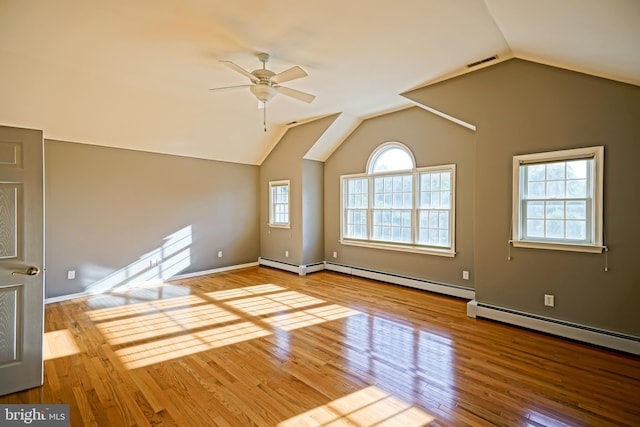 unfurnished living room with ceiling fan, vaulted ceiling, visible vents, wood finished floors, and a baseboard heating unit