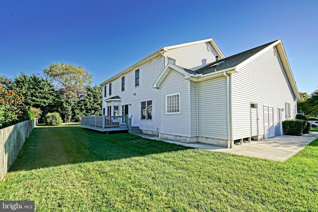 back of property featuring fence, a deck, and a lawn