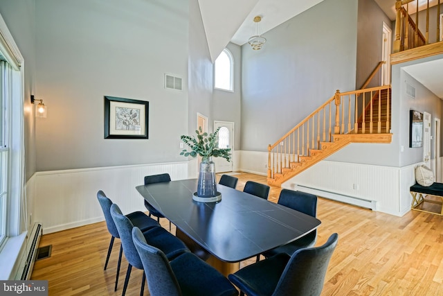 dining area with high vaulted ceiling, light hardwood / wood-style flooring, and baseboard heating