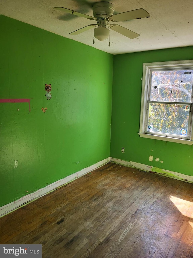 empty room featuring dark wood-type flooring, baseboards, and a ceiling fan