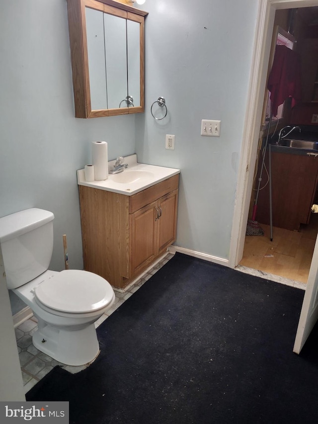 bathroom with toilet, baseboards, and vanity