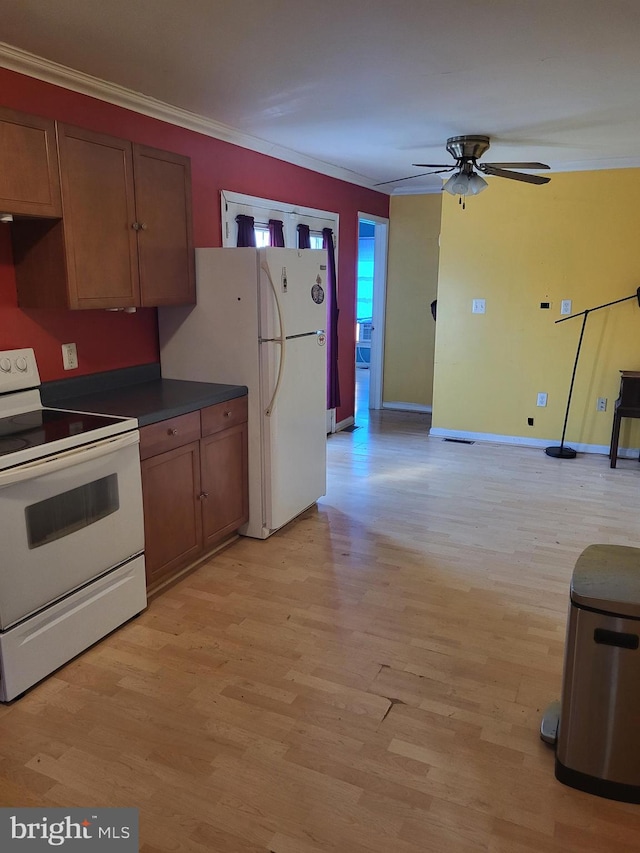 kitchen featuring crown molding, white appliances, dark countertops, and light wood-style floors