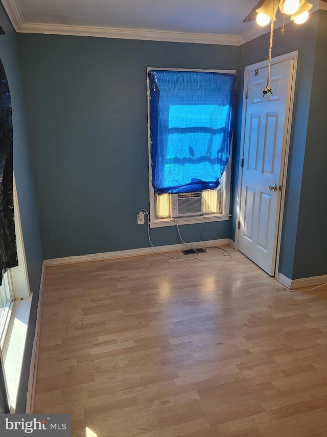 empty room featuring cooling unit, baseboards, crown molding, and wood finished floors