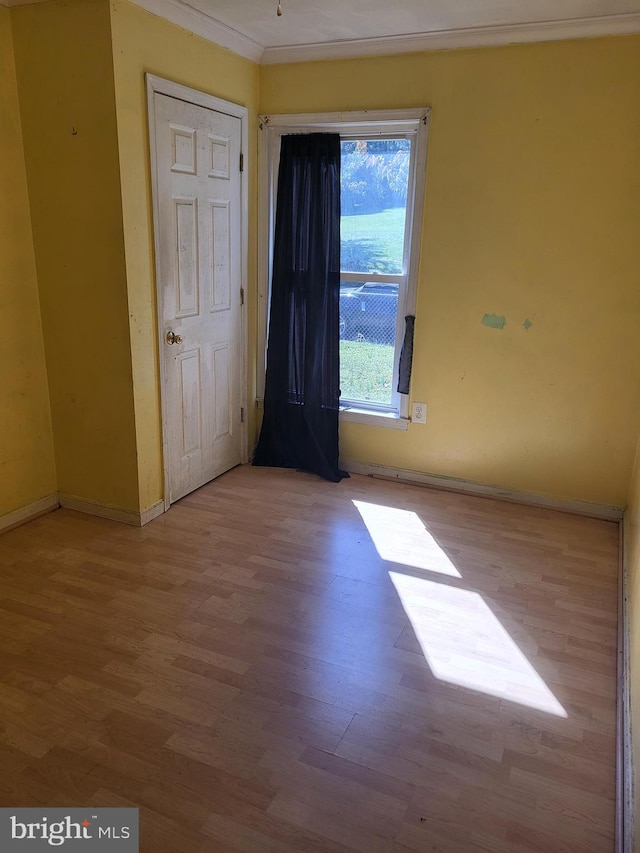 unfurnished room with crown molding, baseboards, and wood finished floors