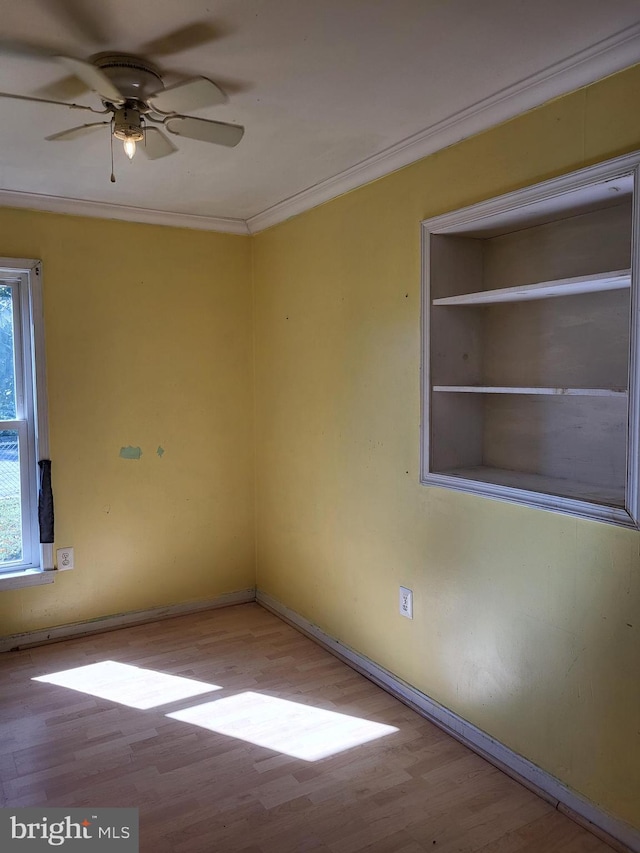 empty room with a ceiling fan, crown molding, baseboards, and wood finished floors