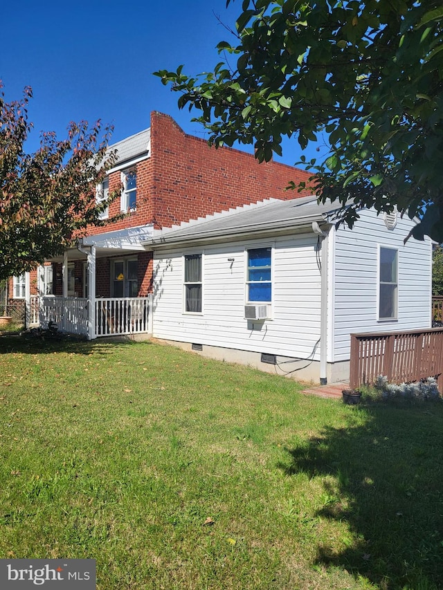 rear view of property featuring a yard, a porch, and crawl space