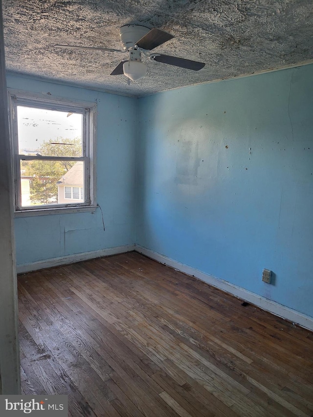 unfurnished room featuring dark wood-style floors, ceiling fan, a textured ceiling, and baseboards