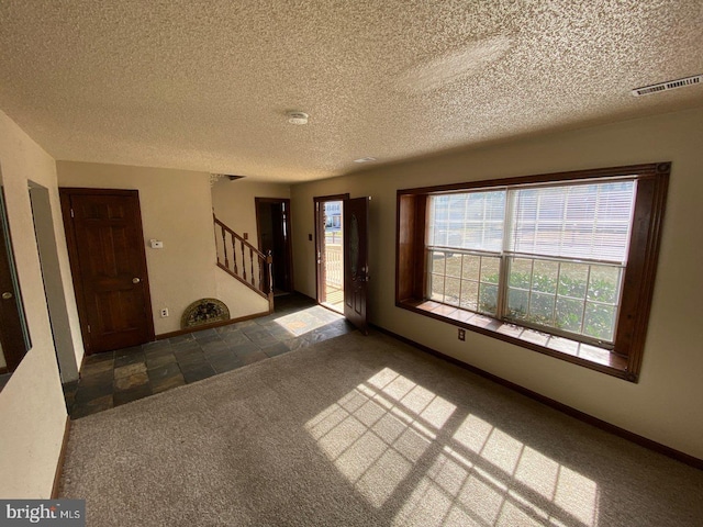 unfurnished living room featuring dark carpet and a textured ceiling