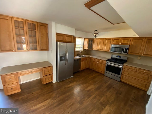 kitchen with sink, stainless steel appliances, built in desk, and dark wood-type flooring