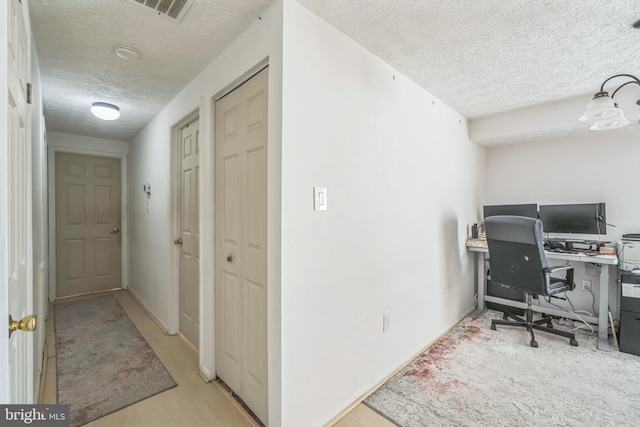 home office with light hardwood / wood-style floors and a textured ceiling