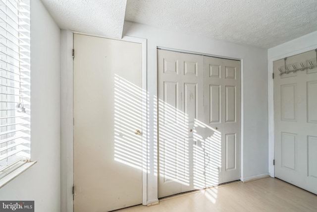 unfurnished bedroom with a textured ceiling and light wood-type flooring