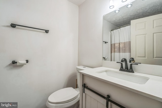 bathroom with toilet, a textured ceiling, and vanity