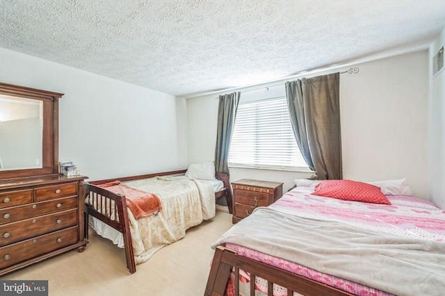 bedroom with a textured ceiling and light colored carpet